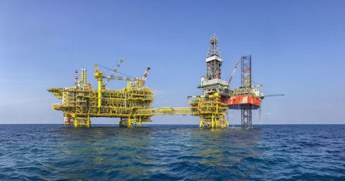 Offshore platform in sea against blue sky