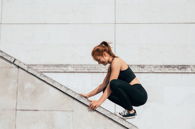 Side view of woman crouching on railing