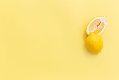 Two halved cuts of lemon with shadow on yellow background. healthy eating, travel, vacation concept