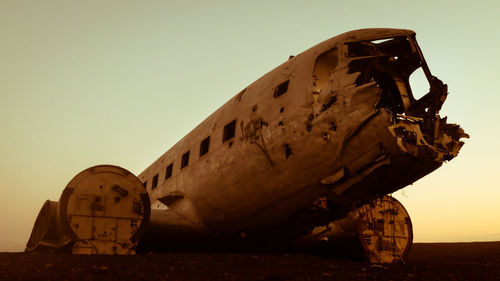 Abandoned airplane against clear sky during sunset