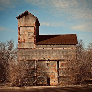 Low angle view of old barn on house against sky