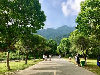 People walking on landscape against sky