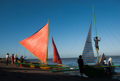 People on boat against clear blue sky