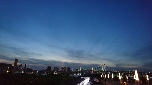 Illuminated cityscape against blue sky