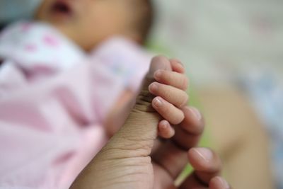 Cropped image of mother holding baby hand