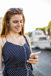 Delighted woman listening to music and browsing social media