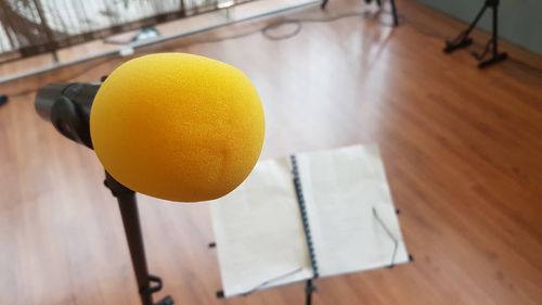 Close-up of yellow microphone by sheet music at recording studio