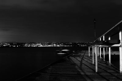 Illuminated bridge over river against sky at night