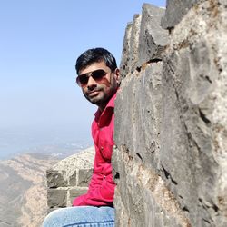 Portrait of young man wearing sunglasses against rock