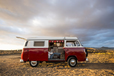 Vintage car on landscape against cloudy sky