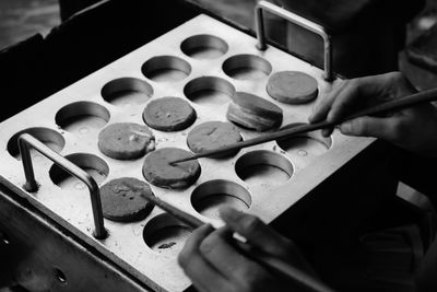 Cropped hands using chopsticks to remove steamed cakes