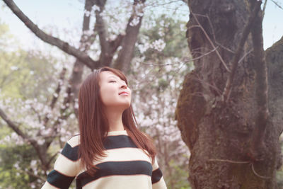 Woman with eyes closed standing in public park