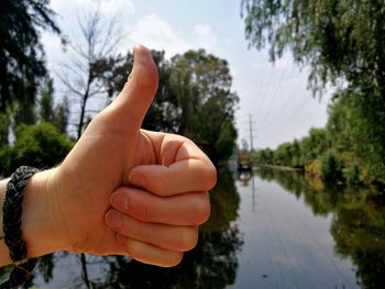 Midsection of person by lake against sky