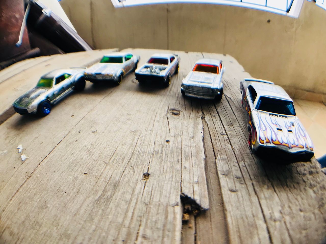 car, mode of transportation, motor vehicle, wood - material, table, land vehicle, indoors, toy car, still life, transportation, no people, toy, high angle view, day, selective focus, technology, communication, finance, connection, garage