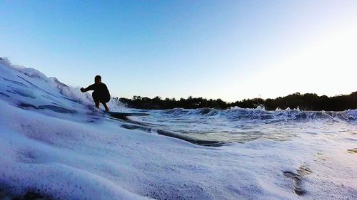 Man standing on snow covered landscape against clear sky
