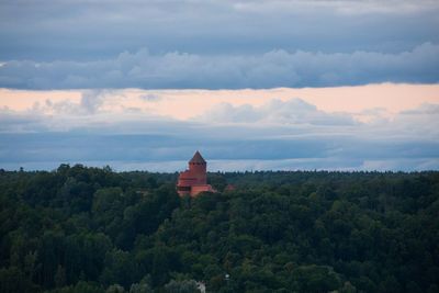 Built structure by trees and building against sky
