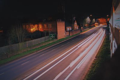 Illuminated road against sky at night