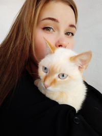 Portrait of woman with cat against wall