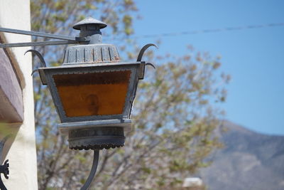 Low angle view of gas light on wall against tree