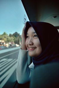 Close-up of teenage girl wearing hijab looking through window in car