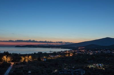 Illuminated cityscape against sky during sunset