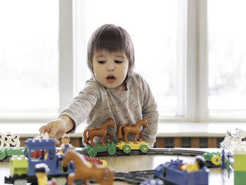 Toddler plays with colorful toy blocks. little boy stares on toy constructor. kindergarten