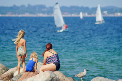 Rear view of people overlooking calm sea