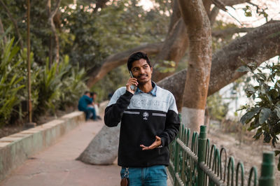 Portrait of young man standing against trees