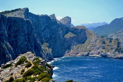 Scenic view of sea and mountains against blue sky