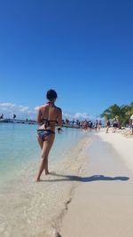 Full length of woman on beach against clear blue sky