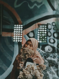 Full length portrait of young woman holding flowers