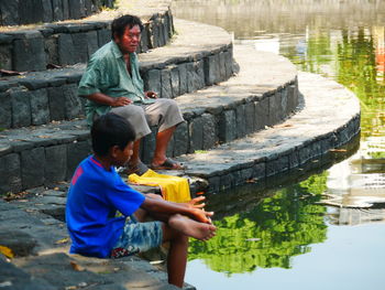 Full length of boy sitting by water