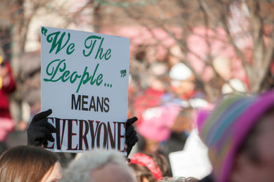 Cropped hands holding placard with text during protest in city