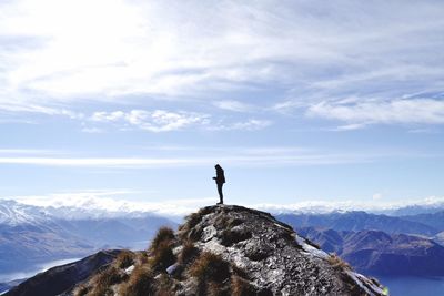 Woman standing on rock against sky during winter