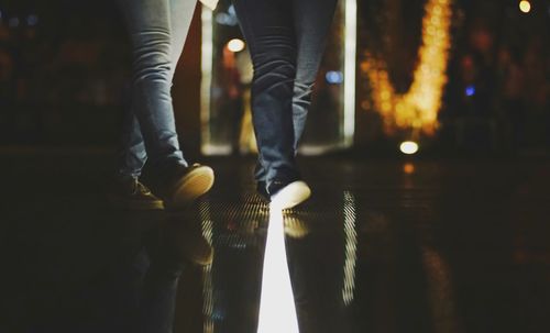 Low section of man standing on illuminated lamp