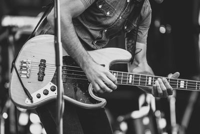 Midsection of musician playing guitar at concert