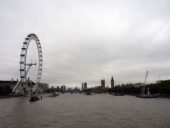 Ferris wheel in city against cloudy sky