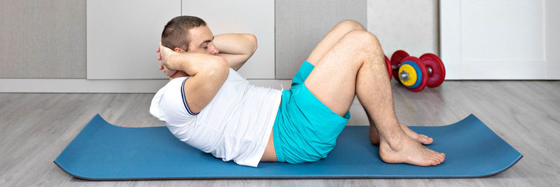 A strong, healthy man with muscles, training at home in the plank position. fitness at home. banner.