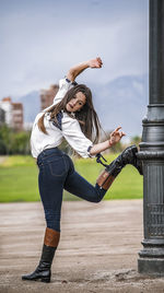 Full length of young woman exercising on field