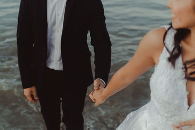 Midsection of couple standing on beach