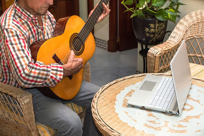 Midsection of man playing guitar