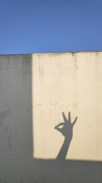 Shadow of people on wall against blue sky
