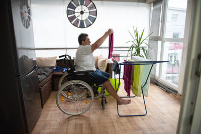 A disabled person on a wheelchair washes laundry