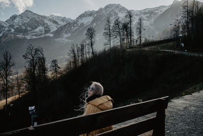 Rear view of woman sitting on snowcapped mountain