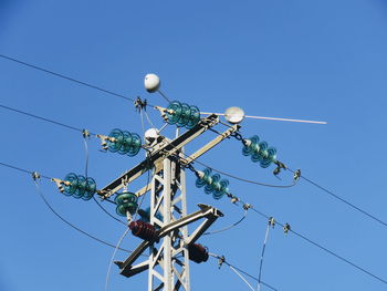 Low angle view of telephone pole against clear blue sky