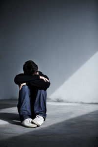 A man looking sad and depressed. a young guy sitting on the floor. mental health and emotion