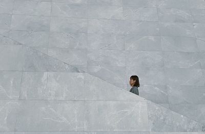 Low angle view of woman standing against wall outdoors