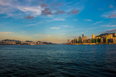 Scenic view of sea by buildings against sky during sunset