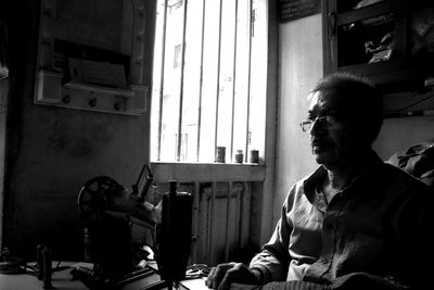 Man sitting by table with sewing machine