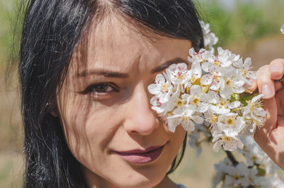 Portrait of a beautiful brunette girl in white flowers blooming pear tree. spring, beauty